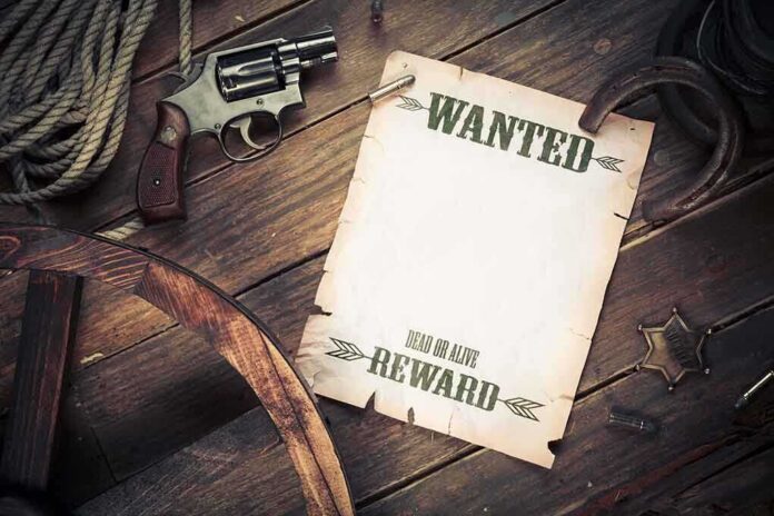 shutterstock_121915636.jpg A vintage wanted poster alongside a revolver and rope on a wooden table