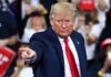 A man in a suit pointing during a speech at a rally