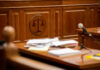 Wooden courtroom desk with papers and a microphone.