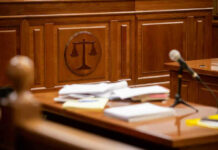 Judge’s SHOCKING Move in CEO Killing Case Wooden courtroom desk with papers and a microphone.