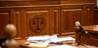 Wooden courtroom desk with papers and a microphone.