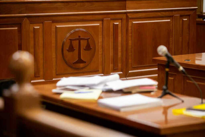 1812892960 Wooden courtroom desk with papers and a microphone.