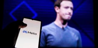 A hand holding a smartphone displaying the Meta logo with a blurred figure in the background
