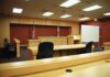 Court’s SHOCKING Corruption Overturns Famous Murder Case Interior view of an empty courtroom with wooden furniture and American flags