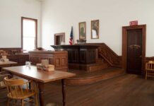 High-Profile Trial Faces Unexpected Delay Interior of a historic courtroom with wooden furniture and an American flag