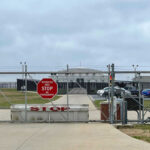 Migrant Death Ruled Homicide Chain-link fence with Restricted Area Stop No Photography sign.