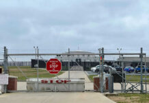 Migrant Death Ruled Homicide Chain-link fence with Restricted Area Stop No Photography sign.