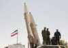 New Intelligence Warns: Missile Threat Isn’t Over Military personnel beside missiles and Iranian flag.