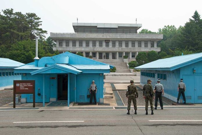 Military personnel standing near blue buildings at a border crossing