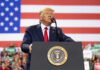 Mount Rushmore Fireworks, Culture War Erupts Man speaks at podium with U.S. flag background.