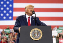 Mount Rushmore Fireworks, Culture War Erupts Man speaks at podium with U.S. flag background.
