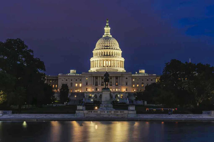 412916230 Illuminated capitol building at night with reflection in water.