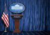 Washington Takes the Wheel on AI White House press briefing podium with U.S. flag and blue curtain