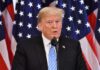A man speaking at a podium with American flags in the background