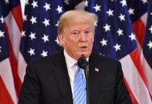 Trump Promises Lower Prices, Bigger Savings A man speaking at a podium with American flags in the background
