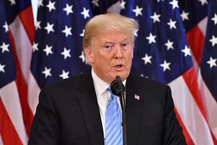 shutterstock_1191272242 A man speaking at a podium with American flags in the background