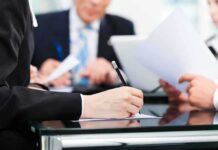 CNBC Praise, Million-Dollar Moves — Then Boom Close-up of a hand writing notes during a business meeting