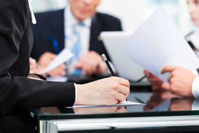 shutterstock_137911247-1 Close-up of a hand writing notes during a business meeting