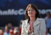 A female politician clapping at a political rally
