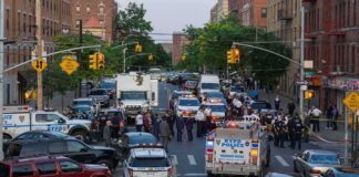 Police vehicles and officers block a city street during an active scene