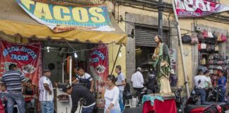 Street taco stand with people and a religious statue