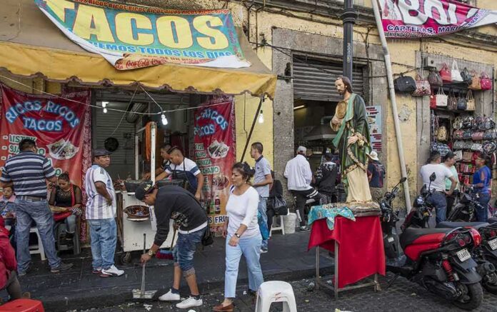 shutterstock_393134476 Street taco stand with people and a religious statue