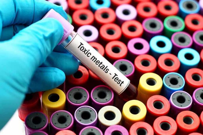 Gloved hand holding blood vial over colorful test tubes