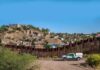 Border Wall Drilling Sparks New Mexico Water Fight border fence with patrol truck in arid landscape