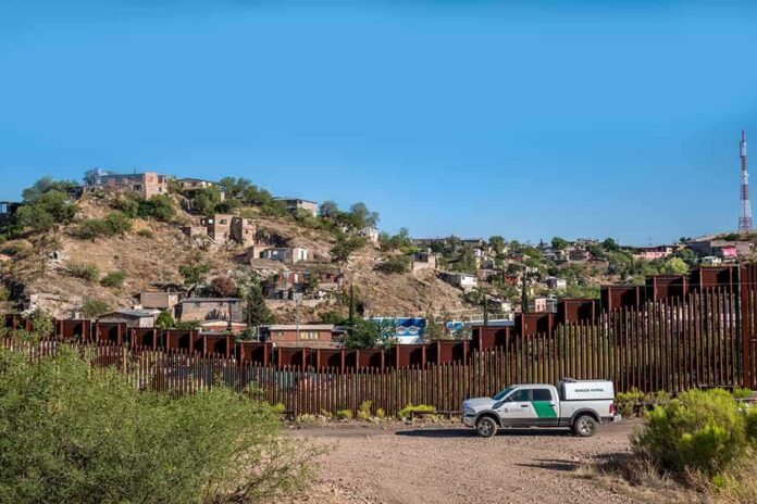 border fence with patrol truck in arid landscape
