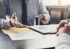 Schools and Agencies Face $400M Legal Claim Business meeting with two people reviewing a document on a clipboard