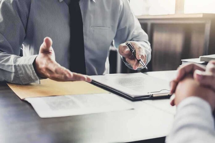 shutterstock_1043656987 Business meeting with two people reviewing a document on a clipboard