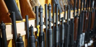 Shotguns and rifles lined up on a rack in a gun store