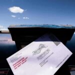 Mail-in ballot being inserted into a blue USPS mailbox