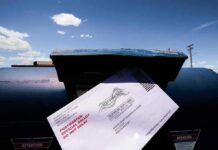 Mail-in ballot being inserted into a blue USPS mailbox