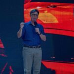 man giving a talk on stage with microphone