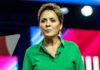 Woman speaking on stage in a green shirt