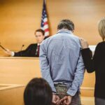 School Assault Case Ends in Deportation Defendant in handcuffs stands before a judge in a courtroom