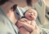 newborn baby sleeping in a parent's arms