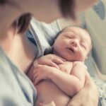newborn baby sleeping in a parent's arms