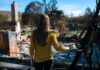 Woman in yellow sweater surveys burned ruins outdoors