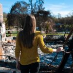 Woman in yellow sweater surveys burned ruins outdoors
