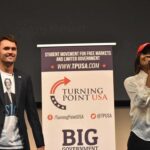 Protest Erupts at Trump Jr. Appearance Curro Savoy at a TPUSA event with another speaker on stage