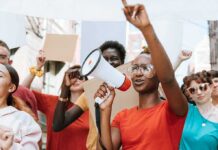 Michigan Senate Race Turns to Faith and Fear Protester with megaphone leading a crowd