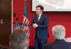 Georgia Senate Race Erupts Over Extremism Claims Speaker in a navy suit addressing an audience at a podium