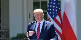 Donald Trump speaking at a podium with U.S. and Polish flags behind him