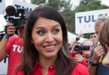 Tulsi Gabbard smiling at an outdoor event surrounded by supporters