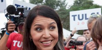 Tulsi Gabbard smiling at an outdoor event surrounded by supporters