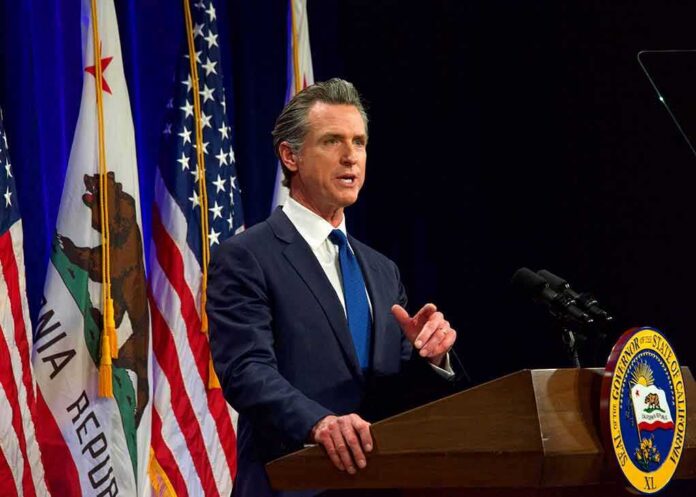 Gavin Newsom speaking at a podium with U.S. and California flags