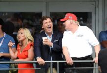 Tucker Carlson laughing beside Donald Trump at a balcony railing during an event