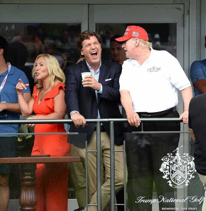 Tucker Carlson laughing beside Donald Trump at a balcony railing during an event